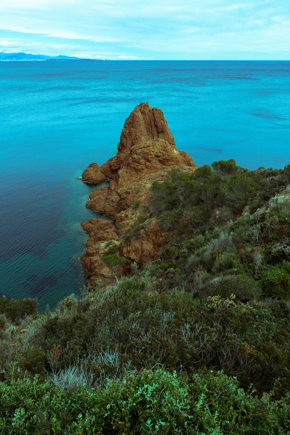 a large body of water sitting next to a lush green hillside