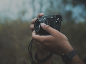 A black-and-white portrait of crazybruce holding a vintage camera in a natural outdoor setting.