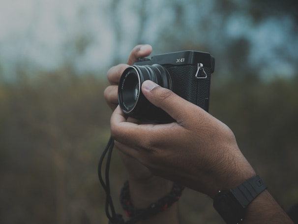 A black-and-white portrait of crazybruce holding a vintage camera in a natural outdoor setting.