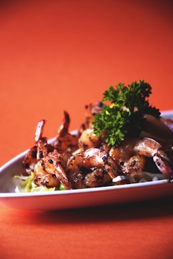Elegant plating of grilled prawns with vibrant African spices on a deep navy plate.