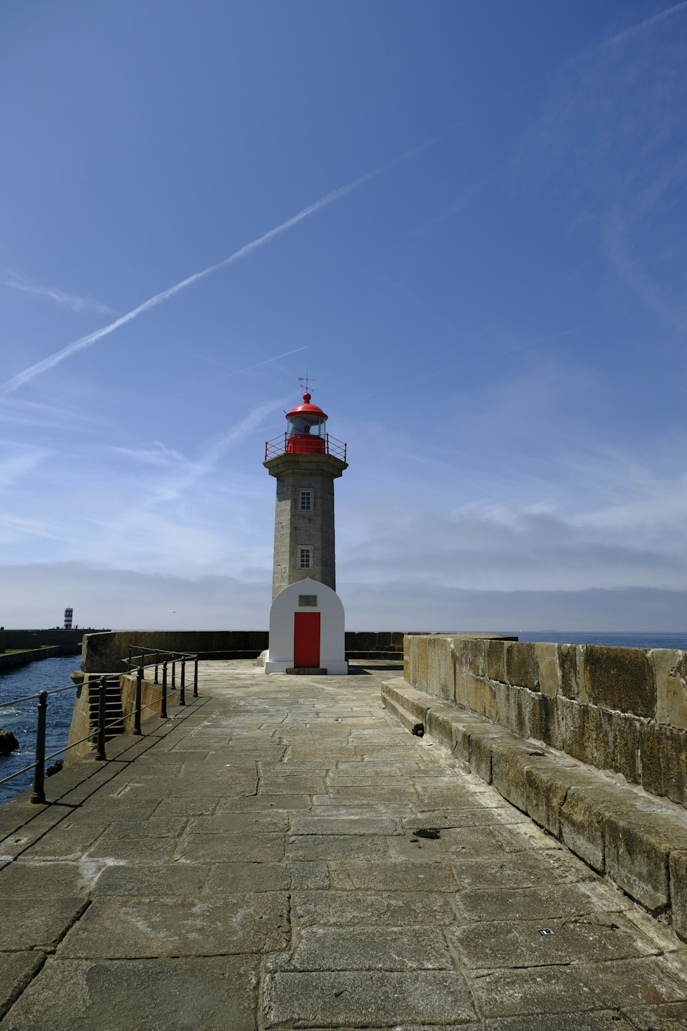 a light house sitting on top of a pier next to the ocean