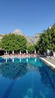 A tranquil outdoor pool surrounded by lush greenery and mountains.