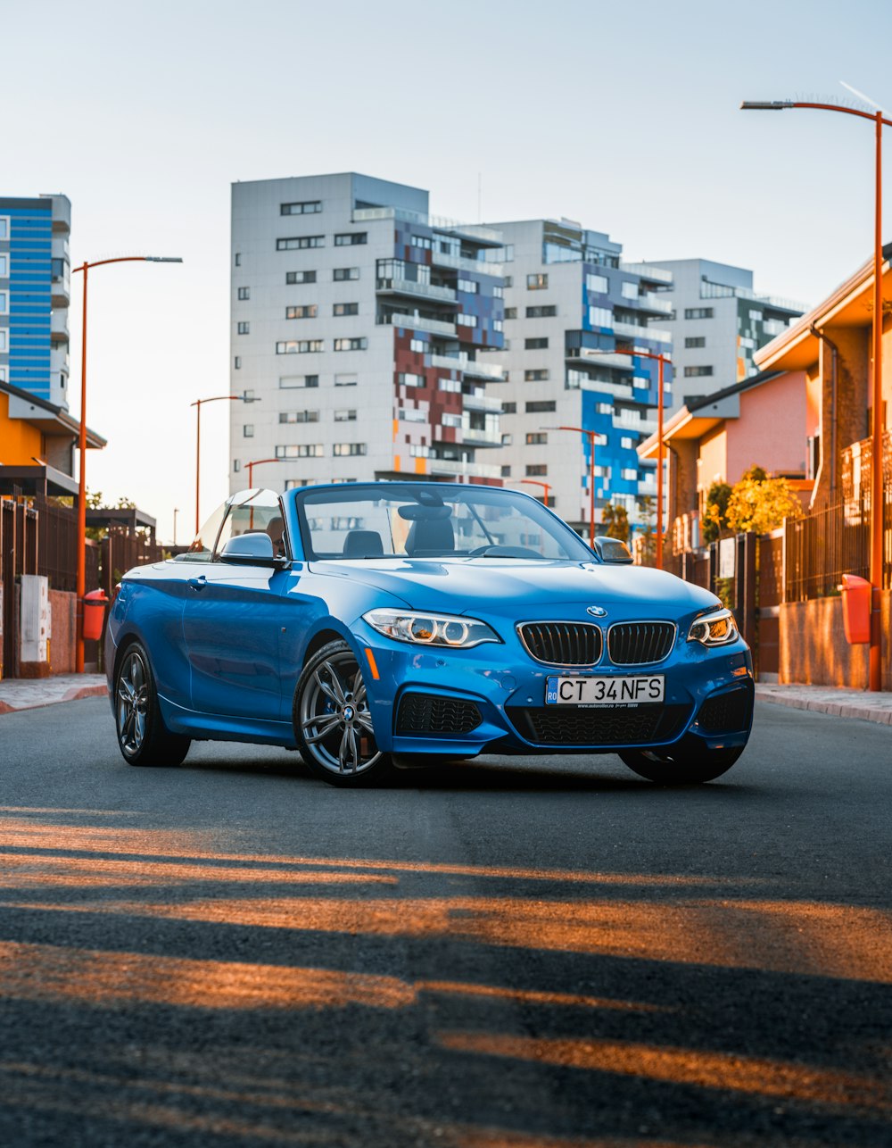 a blue convertible car driving down a city street