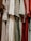 A collection of various dresses is lined up, showcasing a range of patterns and fabrics. The dresses include floral prints, gingham patterns, and solid colors, hung closely together.