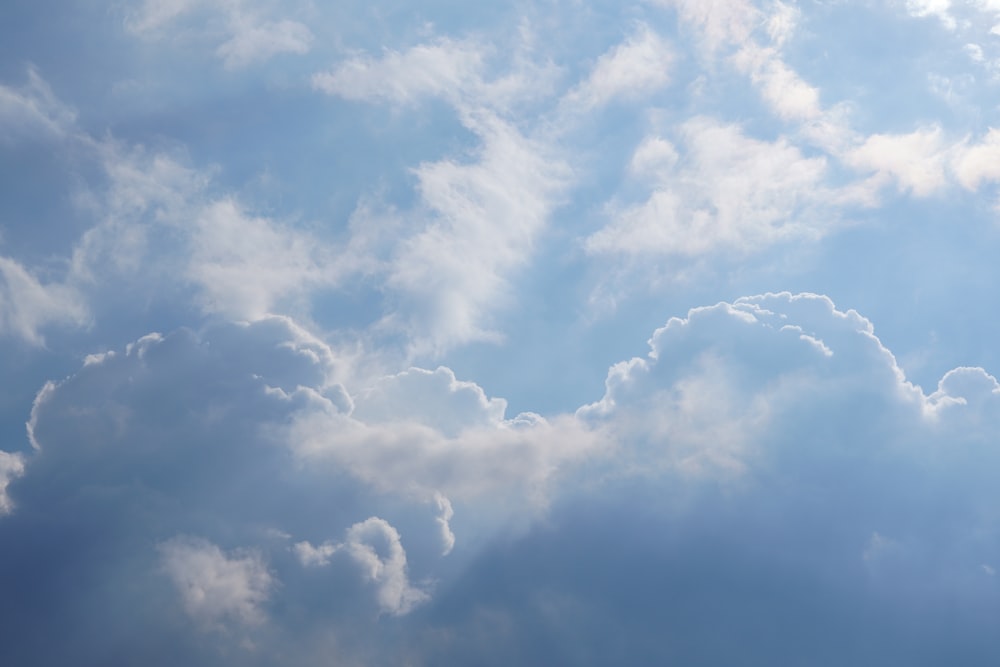 a plane flying through a cloudy blue sky