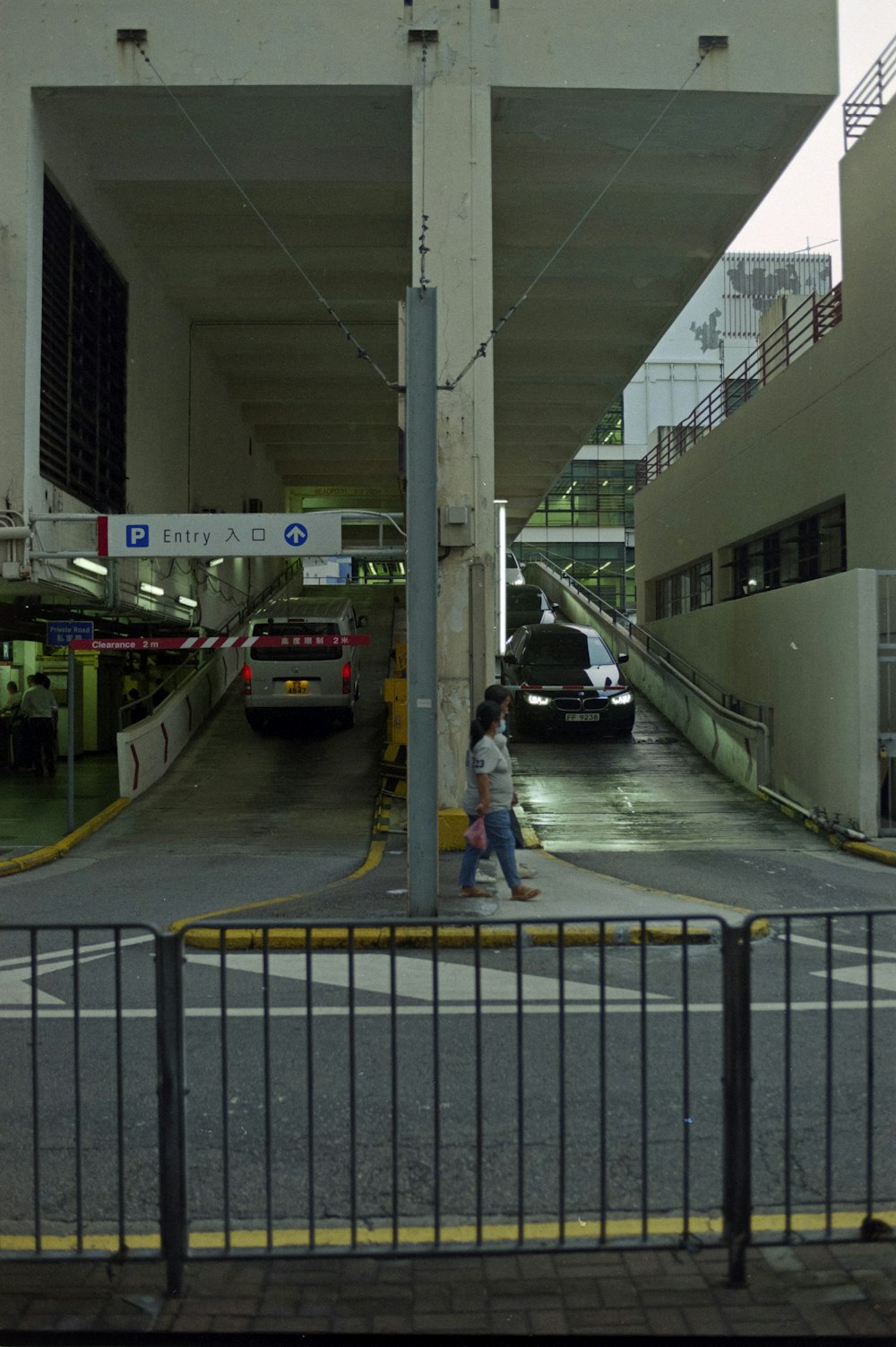 a man walking down a street next to a parking garage