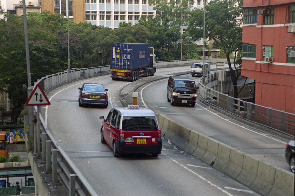 a red van driving down a street next to tall buildings