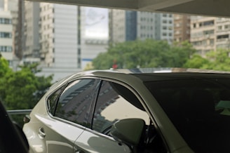 Modern car parked on a city street with clear skies and urban buildings.