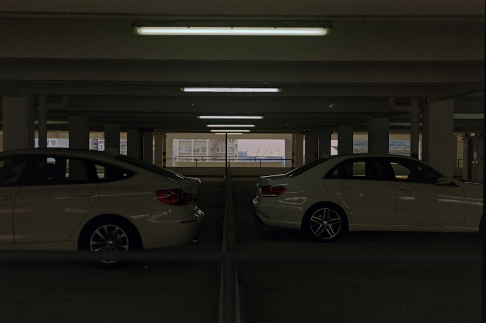 two white cars parked in a parking garage