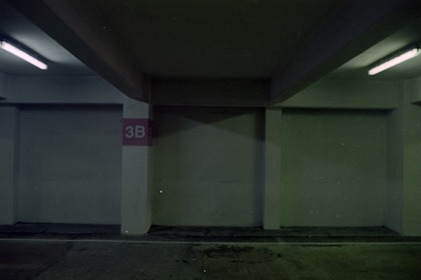 an empty parking garage with a red sign on the wall