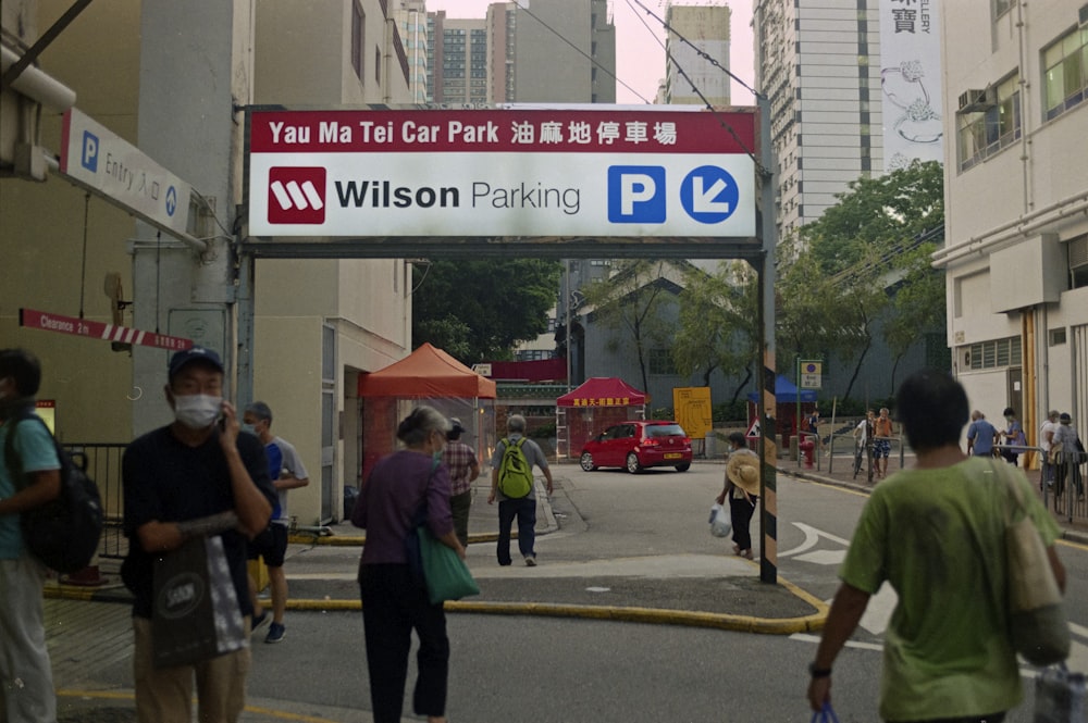 a group of people walking down a street next to tall buildings