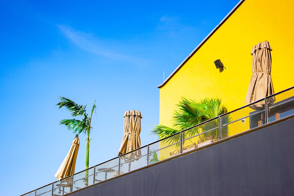 a yellow building with umbrellas and palm trees