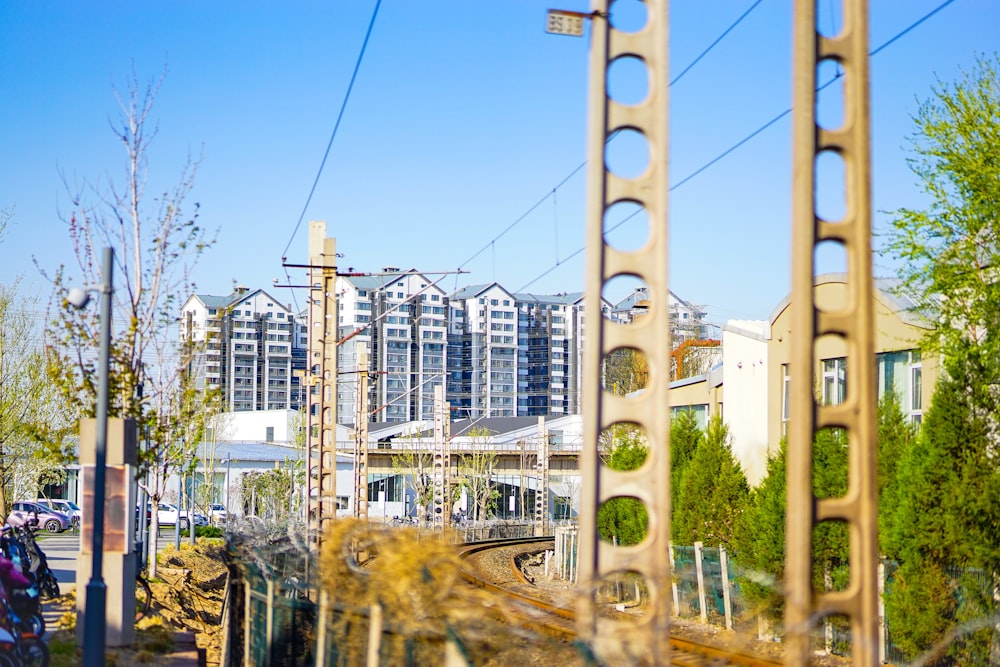a train traveling past tall buildings next to a forest