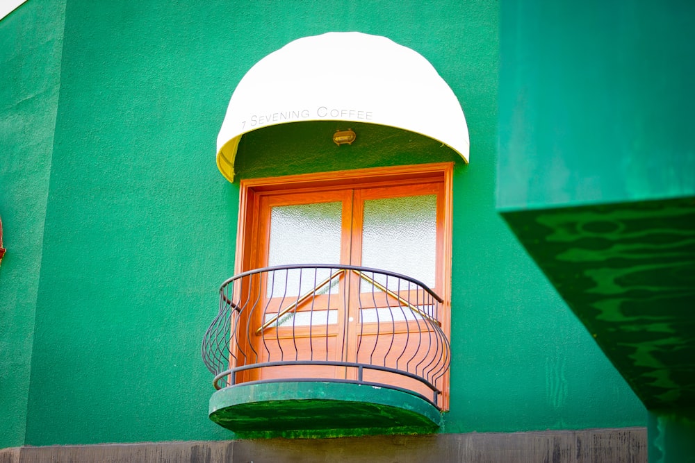 a green building with a balcony and a round window