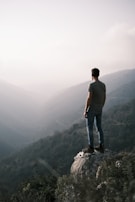 Siddhesh standing at a cliff edge, looking out over a vast valley shrouded in morning mist.