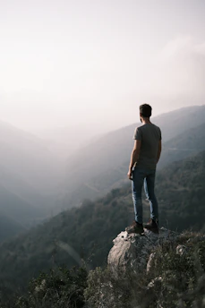 A traveler standing on a cliff at sunrise, overlooking a vast, misty valley.