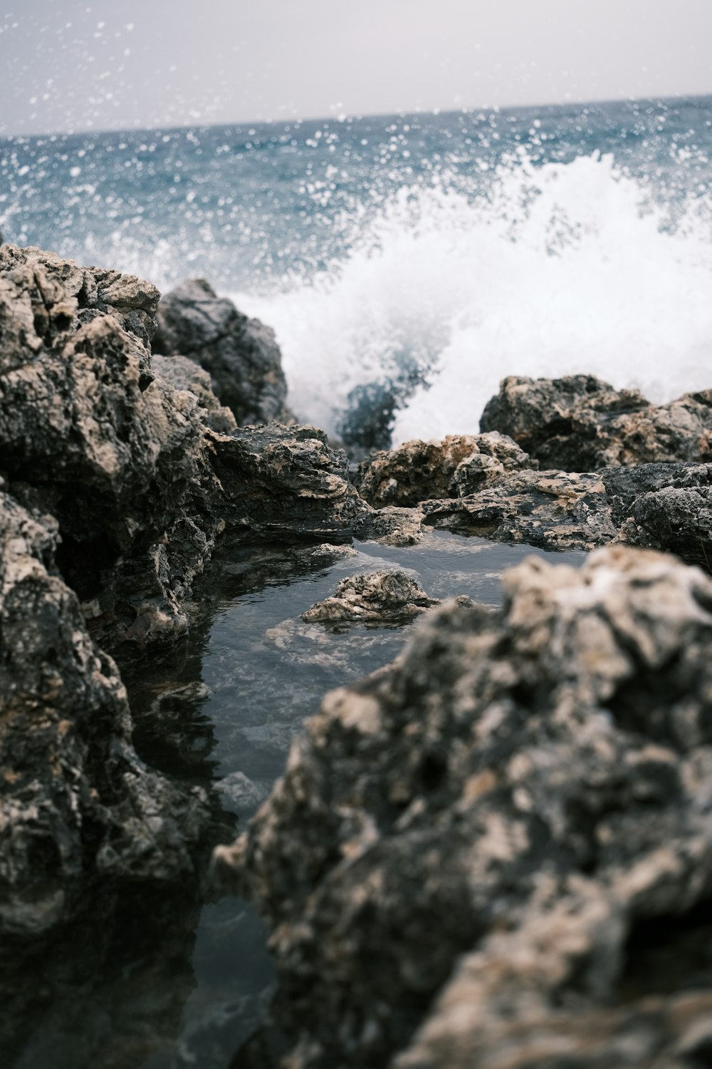 a wave crashing over rocks on the beach