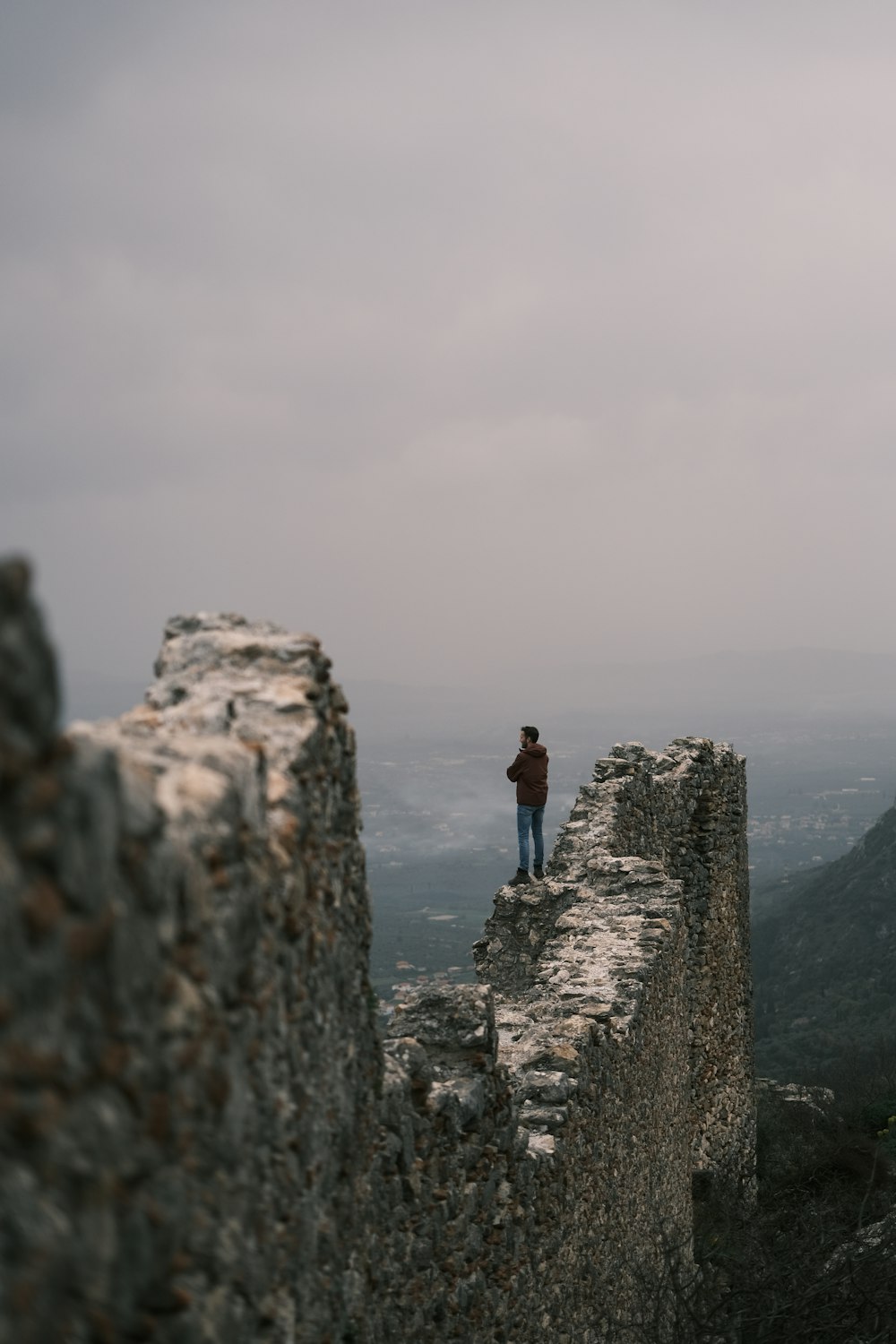 uma pessoa em pé no topo de uma parede de pedra