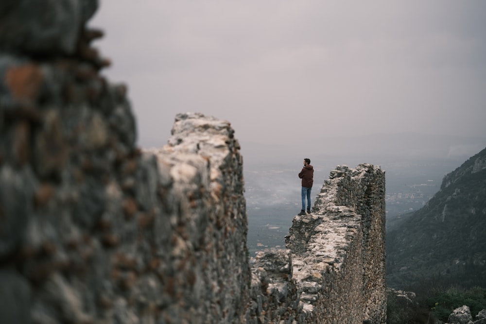 a man standing on top of a stone wall