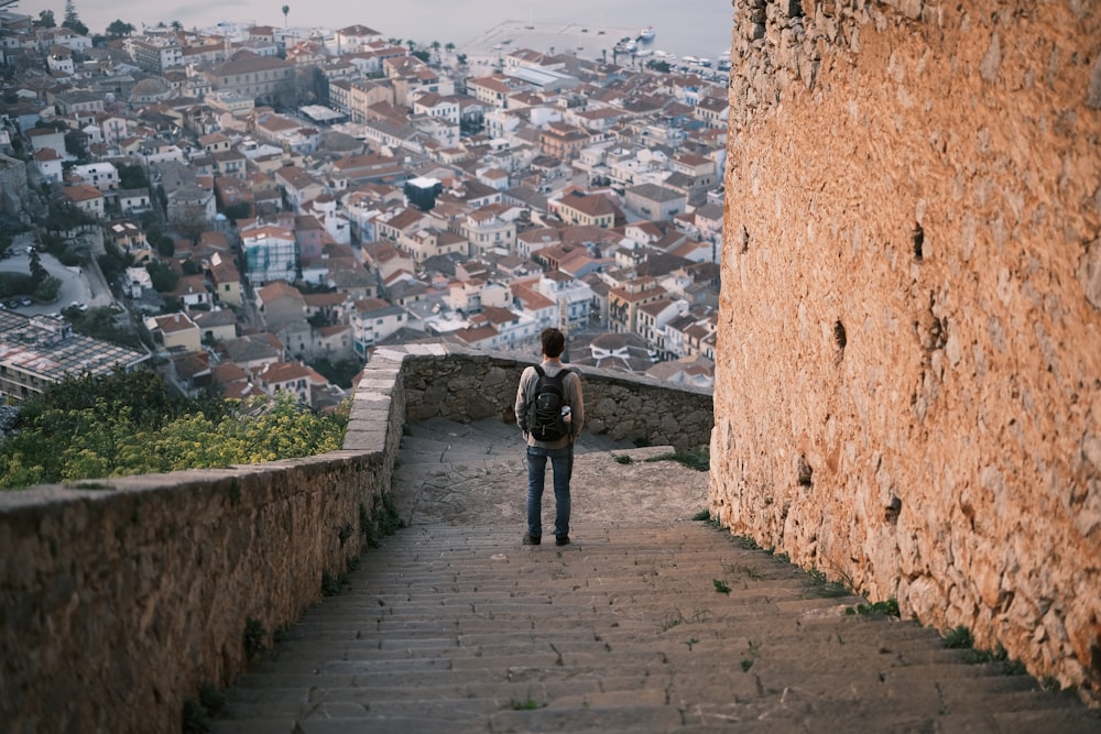 a person standing on a stone wall with a city in the background