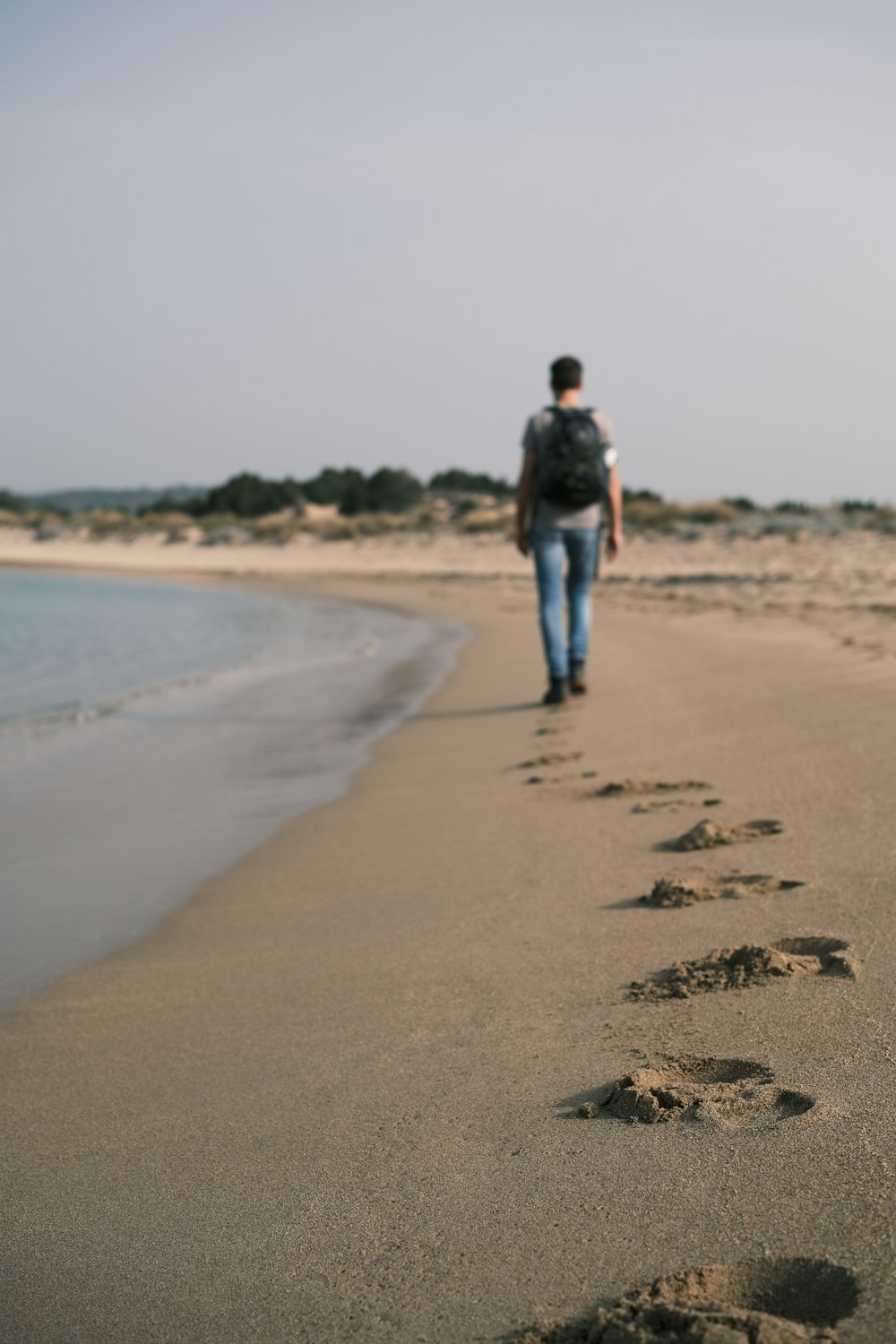 a man walking down a beach next to the ocean
