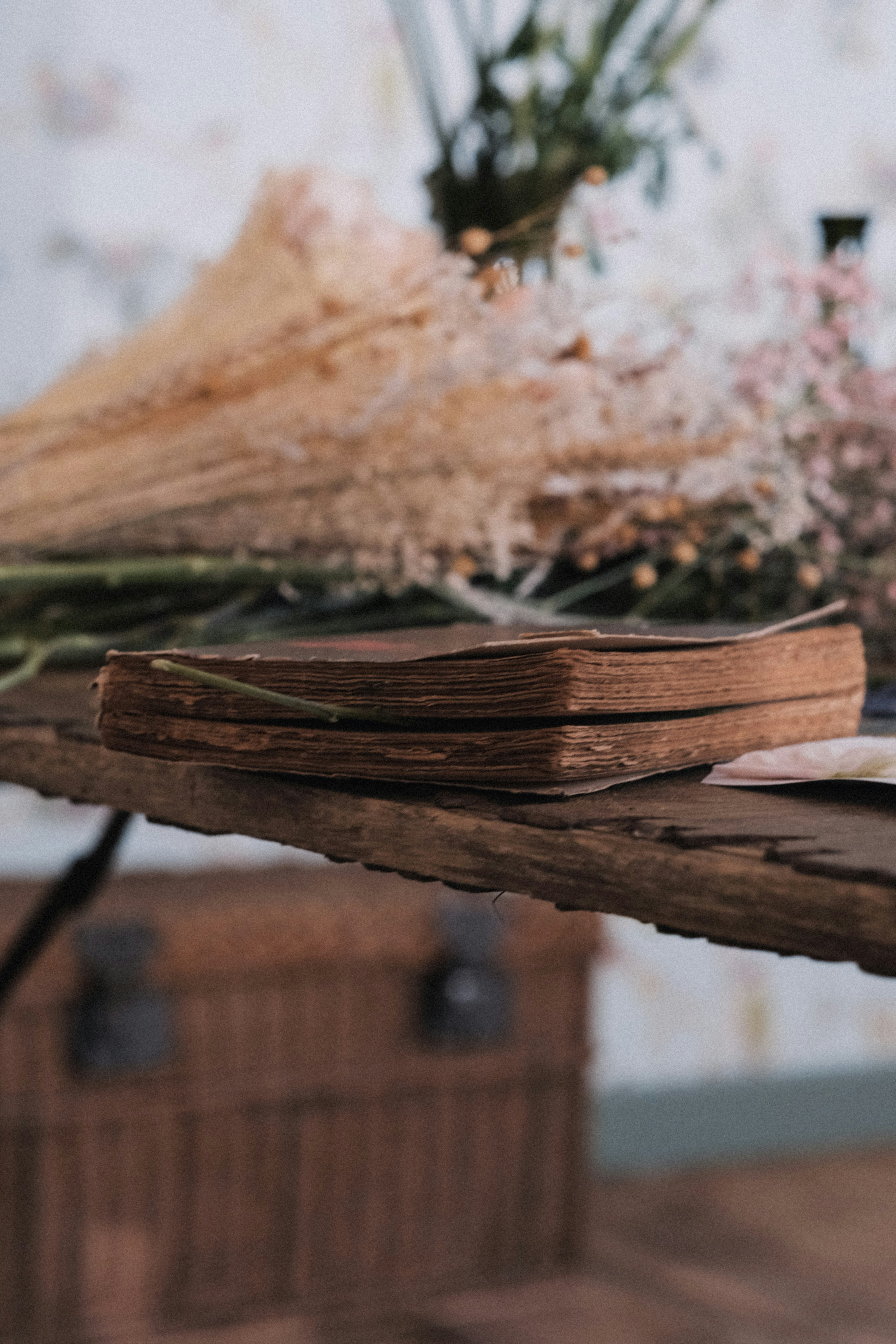 Stack of rustic farming guide books on wooden table with dried herbs, warm golden light