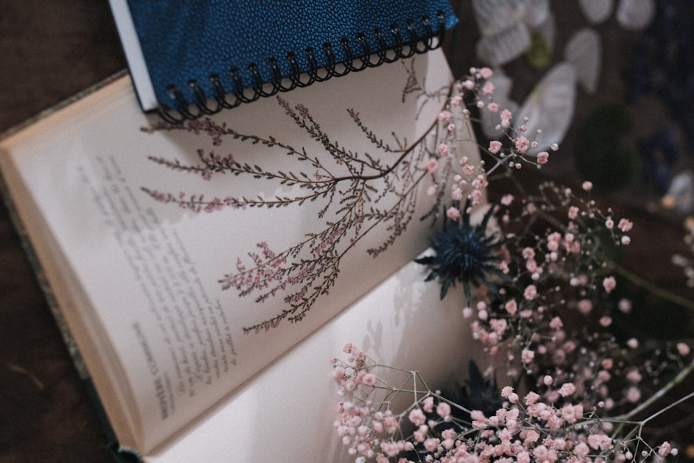 a book opened on top of a table next to a bouquet of flowers