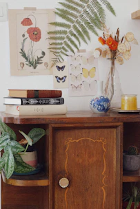 A rattan side cabinet with natural textures, styled with plants and books on top.