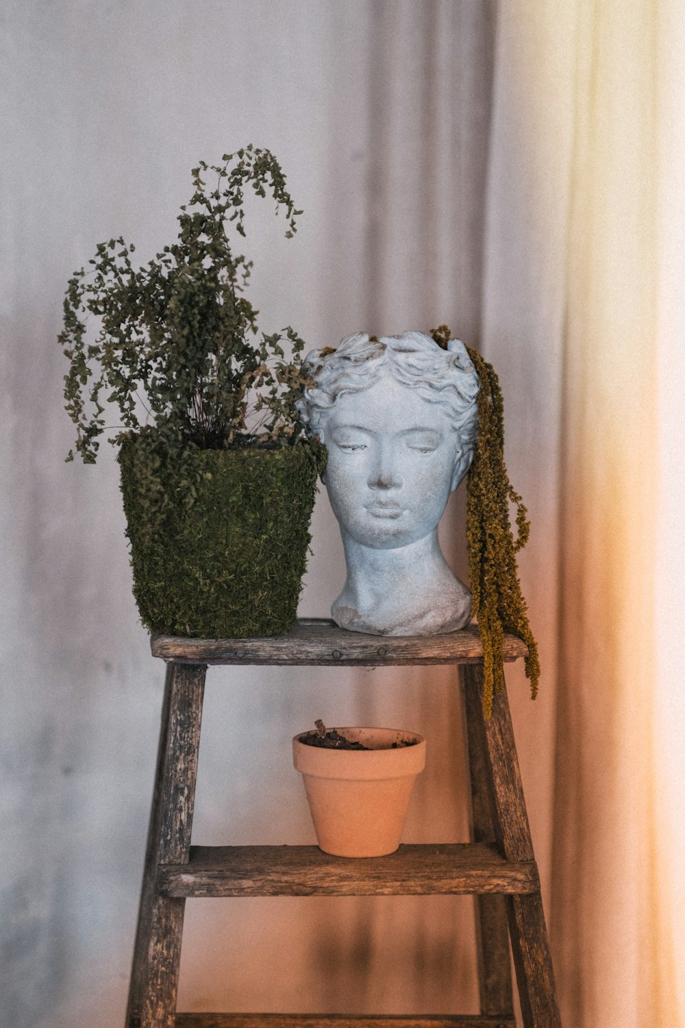 a statue of a woman sitting next to a potted plant