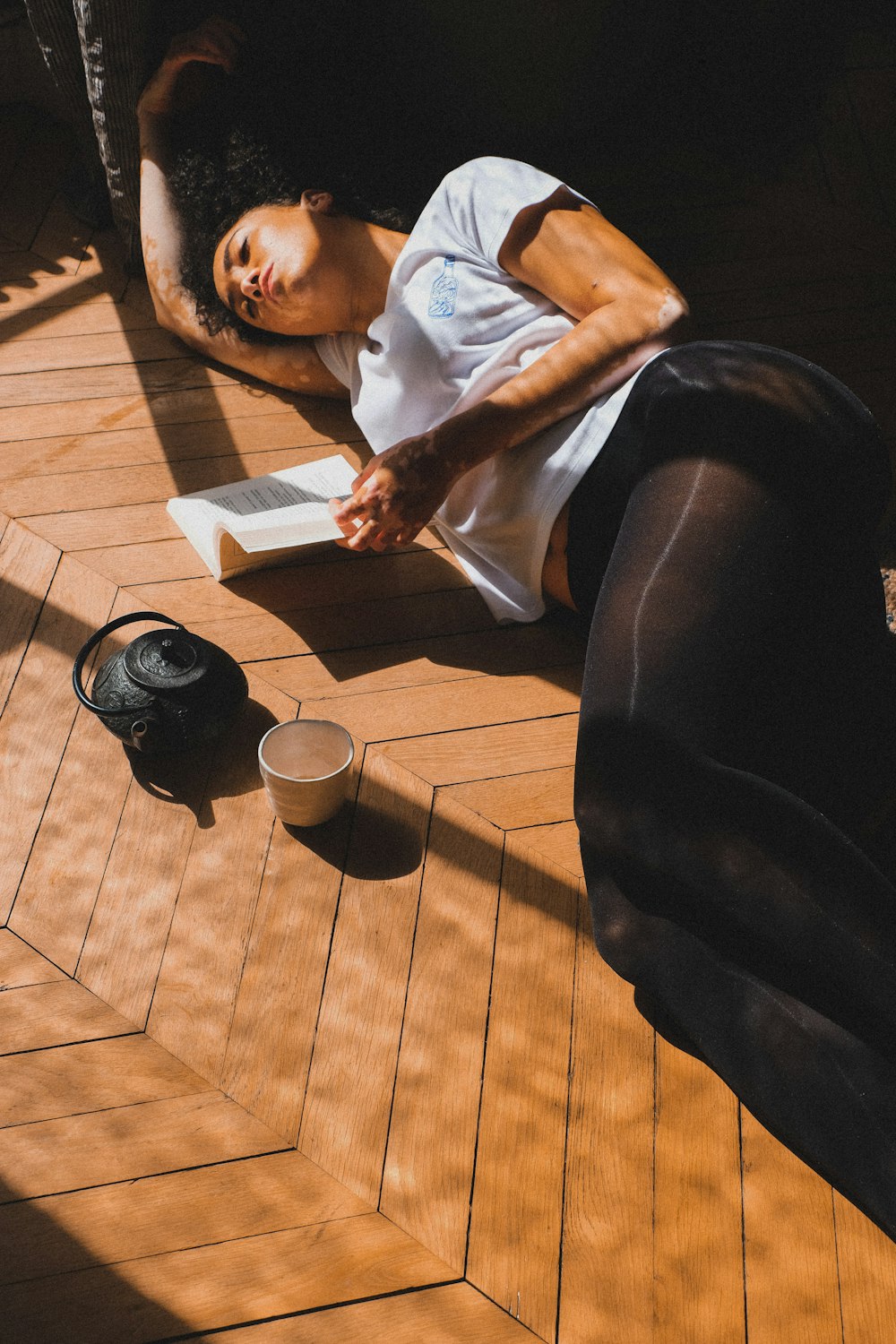a woman laying on the floor next to a cup of coffee