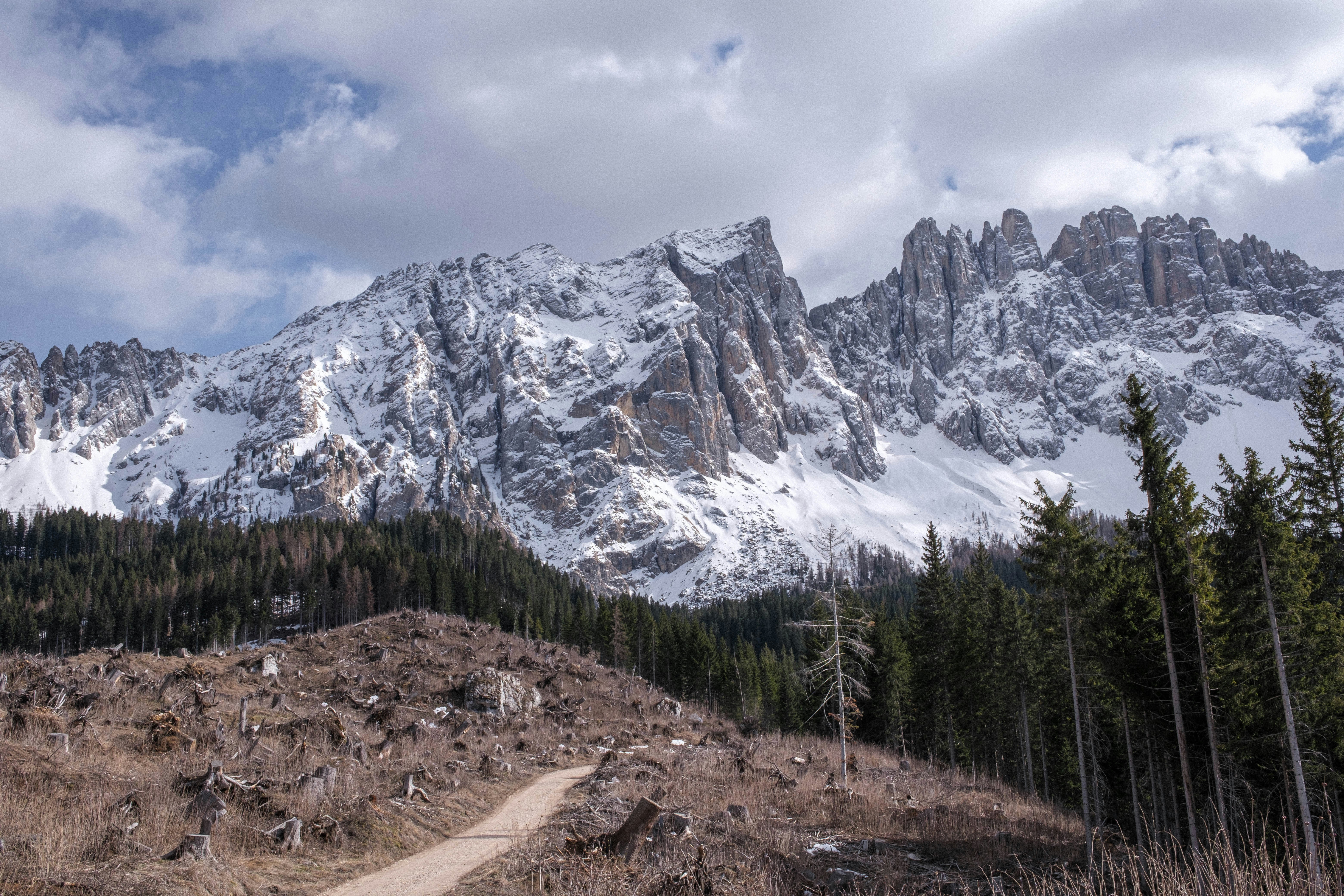 a dirt road in front of a snow covered mountain