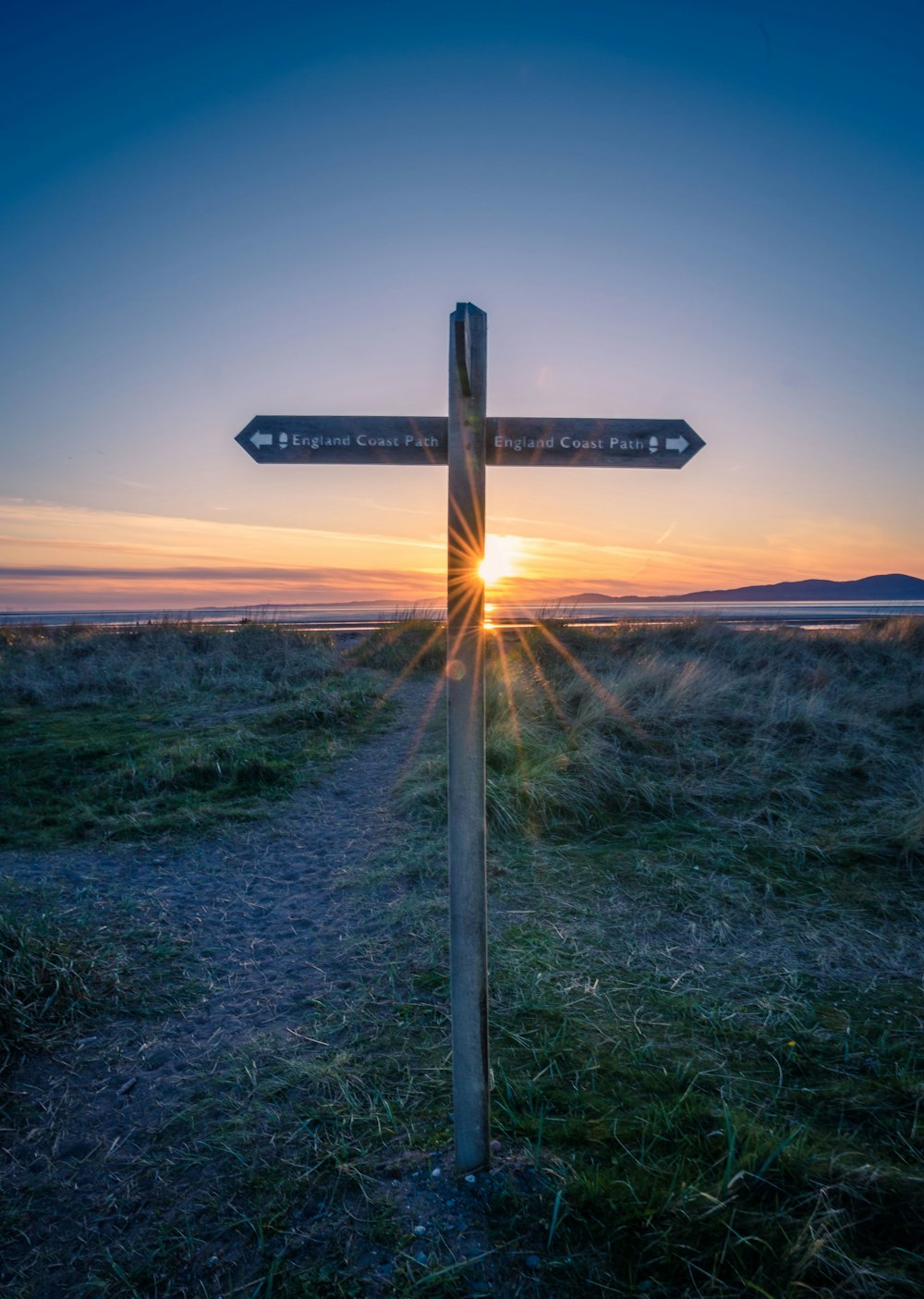 a wooden cross with a sunset in the background