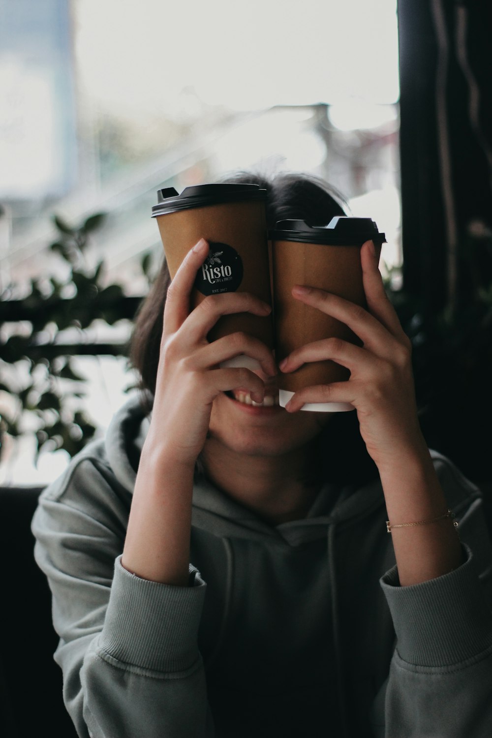 a woman covering her face with two coffee cups