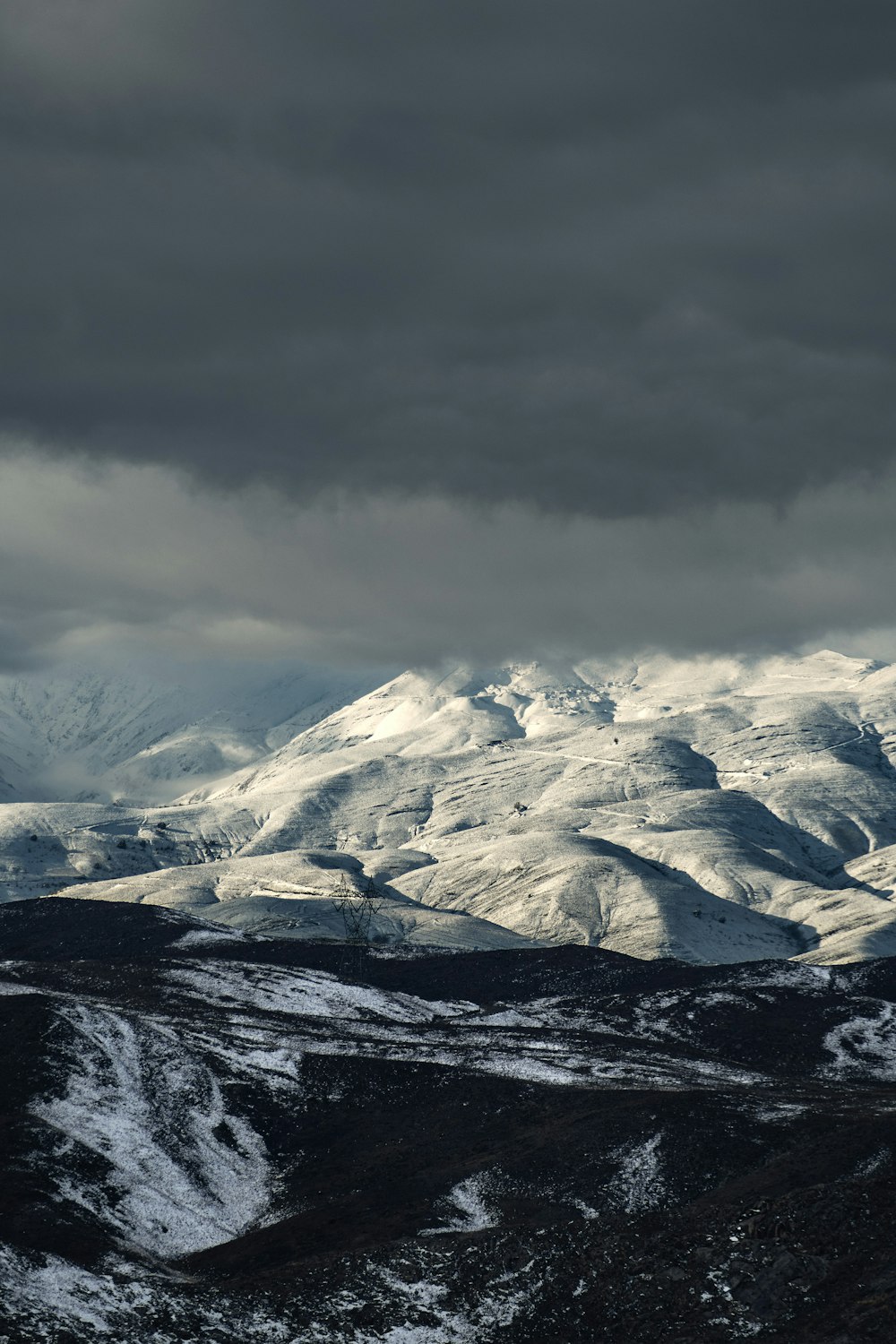 a snowy mountain range under a cloudy sky