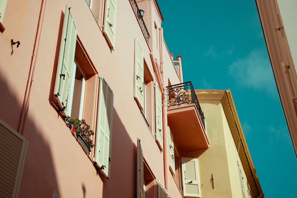 um edifício cor-de-rosa com persianas e uma varanda