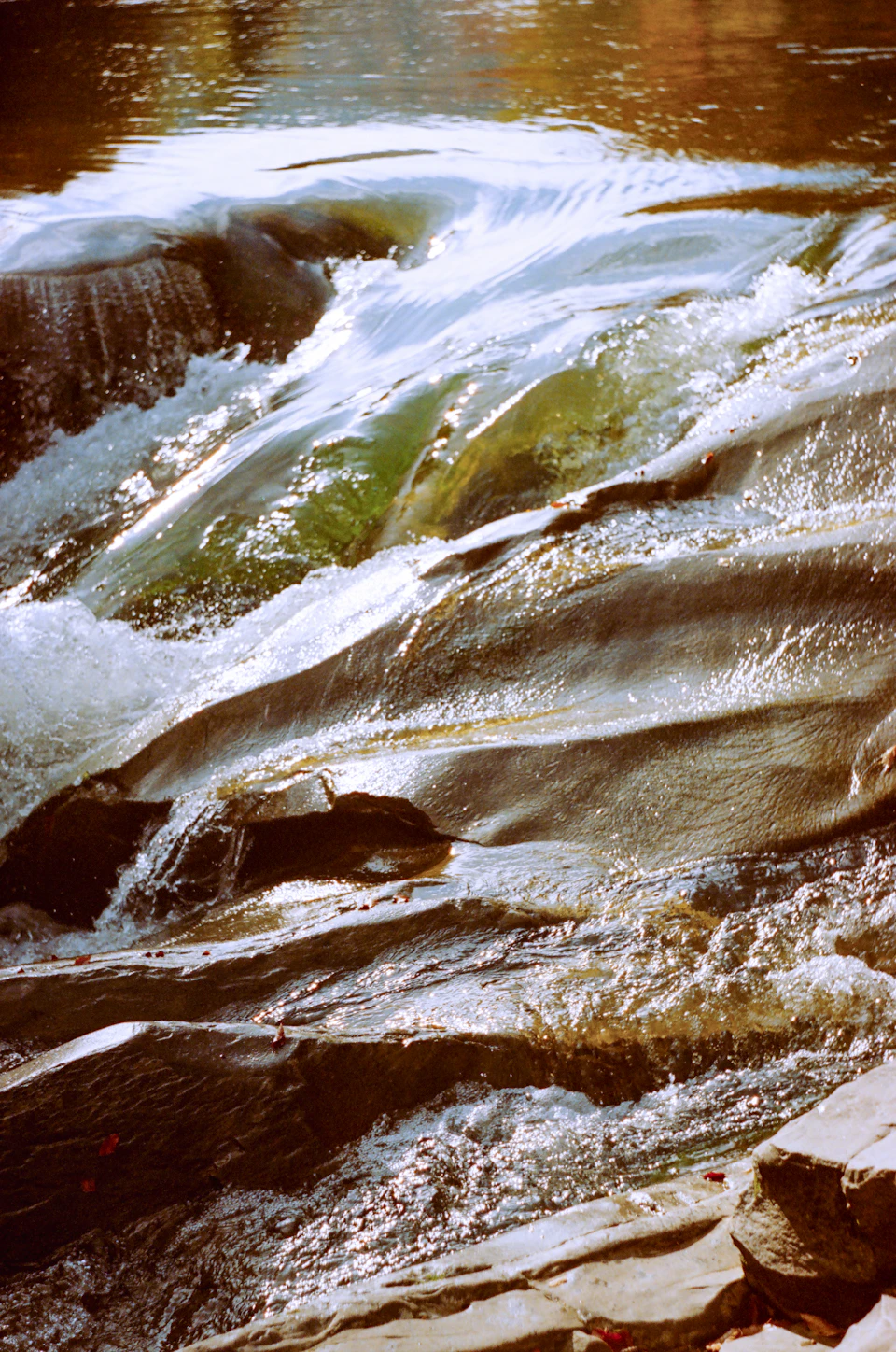 River flows over rocks, creating a frothy white wave on its surface
