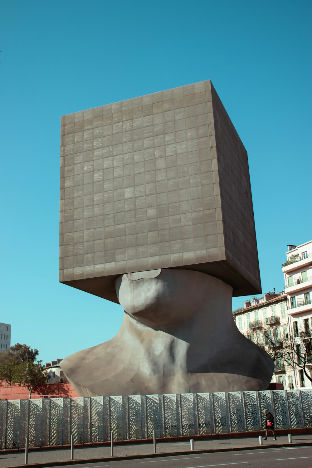 a large sculpture of a person's head in front of a building