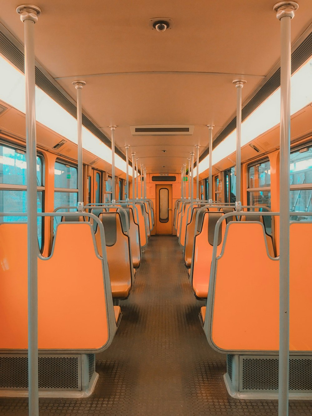 an empty train car with orange seats and metal poles