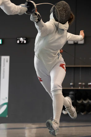 Close-up of focused athletes competing fiercely in a regional fencing tournament.