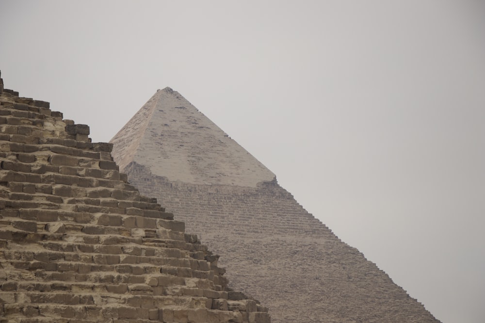 two large pyramids in front of a cloudy sky