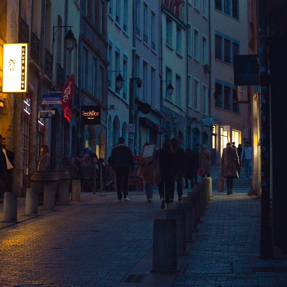 a group of people walking down a street next to tall buildings