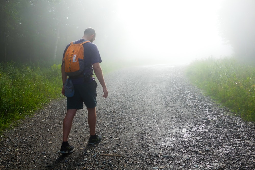 a man with a backpack walking down a foggy road