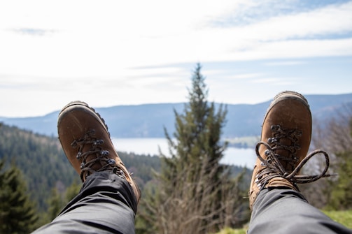 a person wearing hiking shoes standing on a mountain