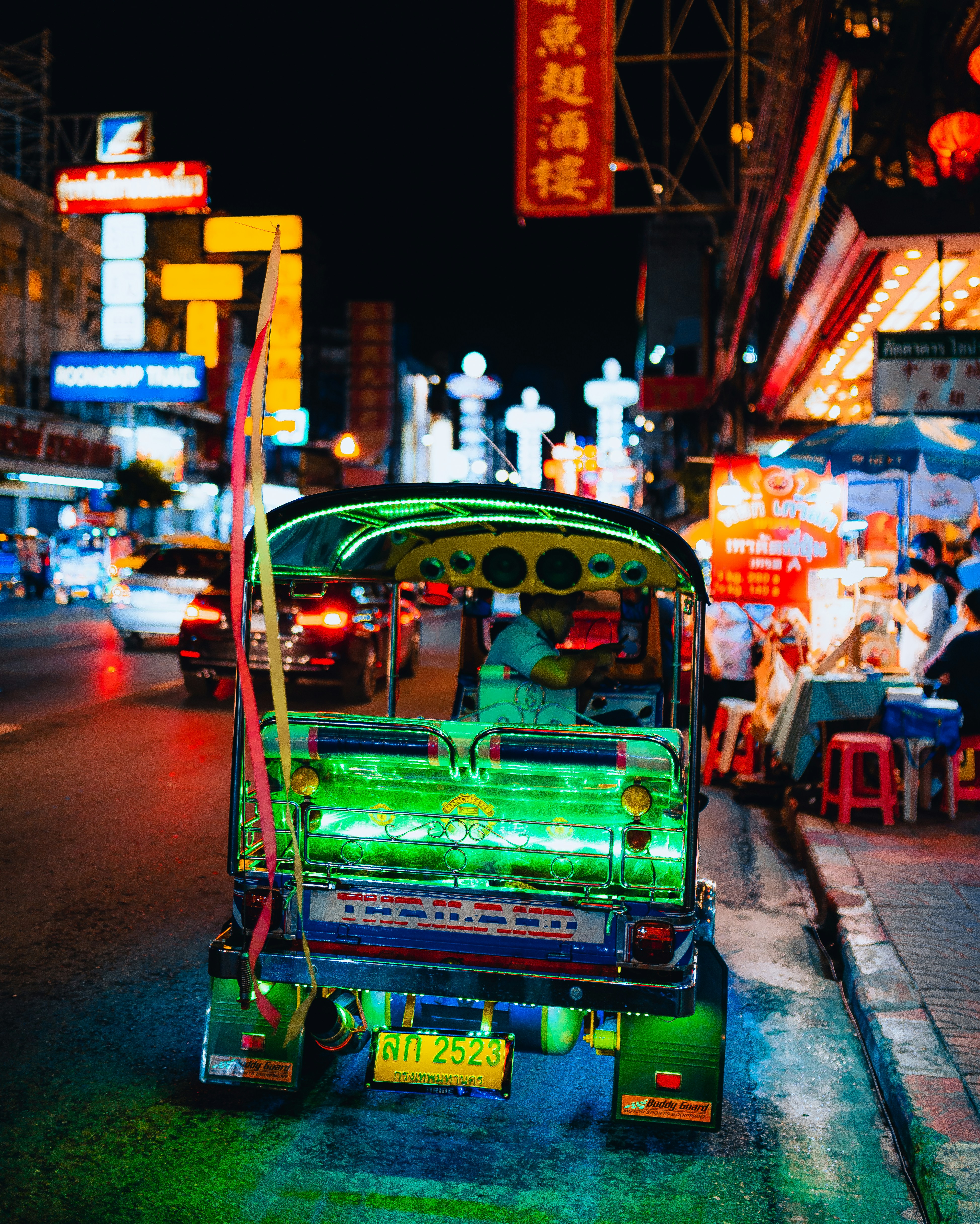 a tuk tuk parked on the side of the road at night
