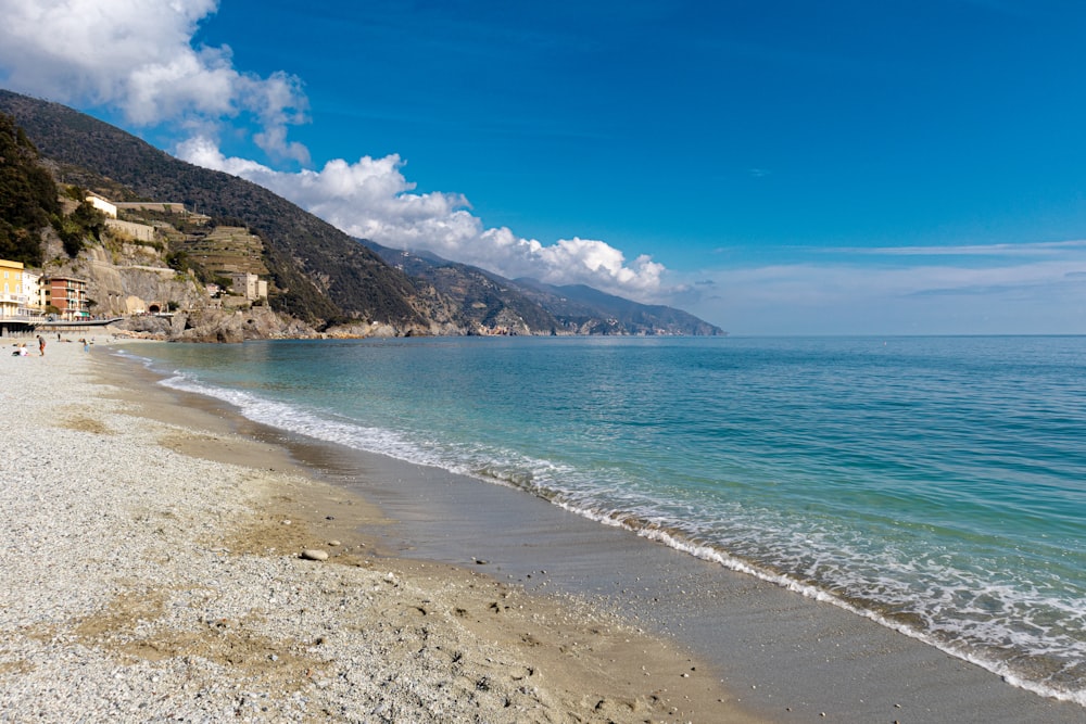 a sandy beach next to the ocean under a blue sky