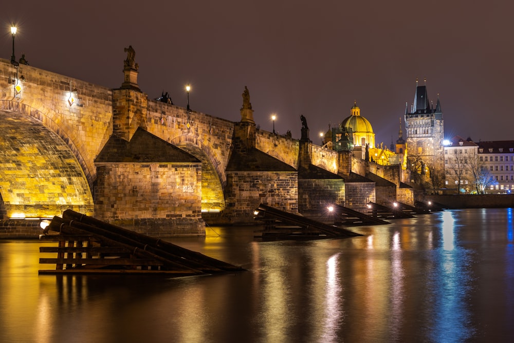 a night scene of a city with a bridge and buildings