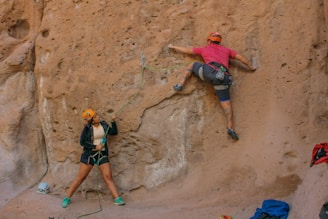 a couple of people that are climbing up a rock