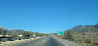 A wide shot of a freshly paved highway stretching into the horizon under a clear blue sky.