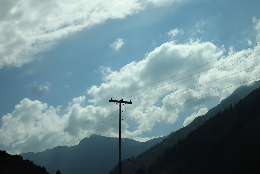 a telephone pole in the foreground with a mountain in the background