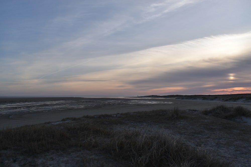 the sun is setting over the beach and water